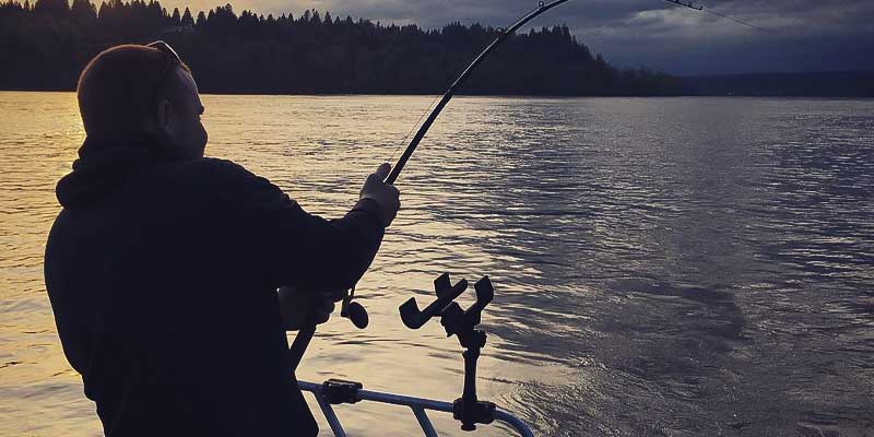 Man fishing at dusk on a river