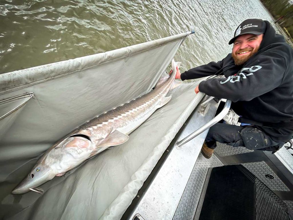 a man smiling and holding a fish