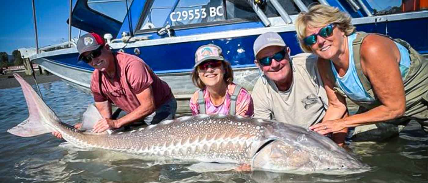 Early Bird Sturgeon Fishing Special Group of 4 people posing in the water with a sturgeon they caught
